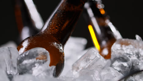 Primer-Plano-De-Botellas-De-Vidrio-De-Cerveza-Fría-O-Refrescos-Enfriándose-En-Un-Cubo-Lleno-De-Hielo-Sobre-Fondo-Negro-1